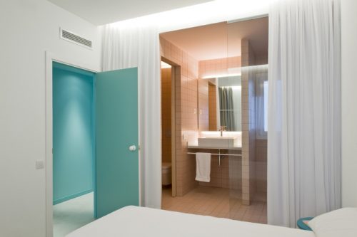 strakke-minimalistische-slaapkamer-met-een-half-open-roze-badkamer